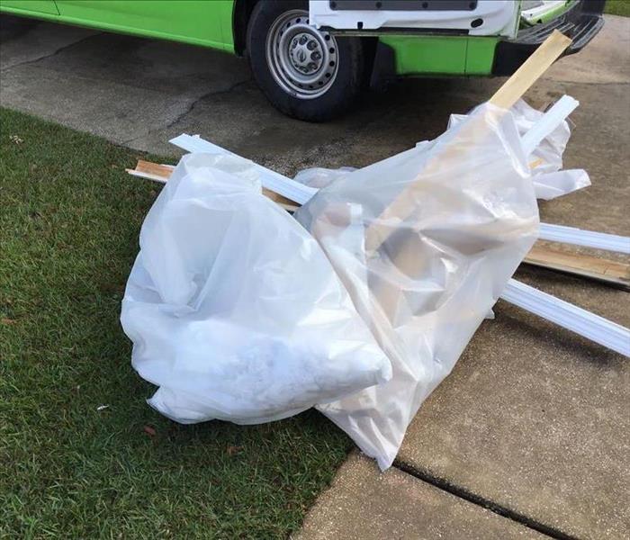 water damaged wood and bagged debris in clear plastic bag on grass