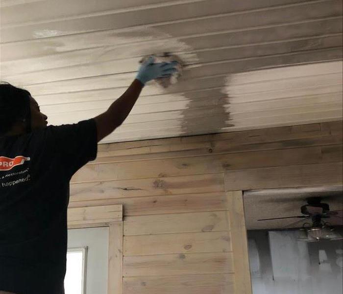 women wiping soot damage off of kitchen ceiling