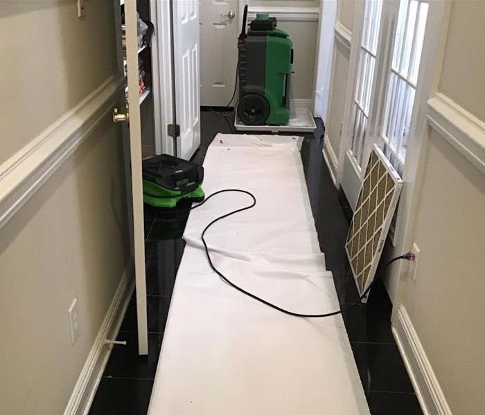 narrow hallway with black tile and white polyvinyl covering it