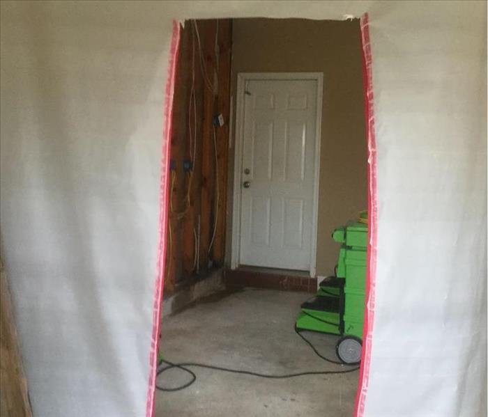 white plastic containment area with doorway cut and trimmed in red tape