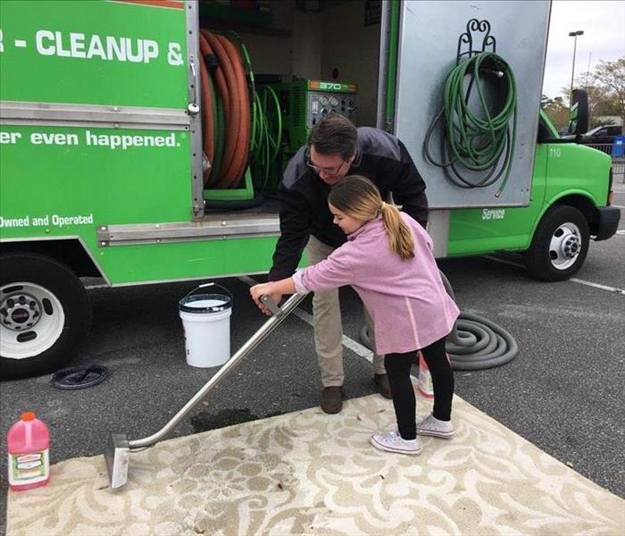 man helping little girl use carpet wand to clean a rug